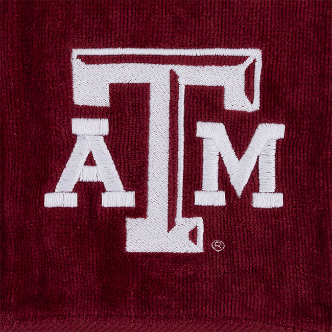 A close-up of a maroon textured fabric item featuring a large white embroidered Texas A&M 'A&M' logo.