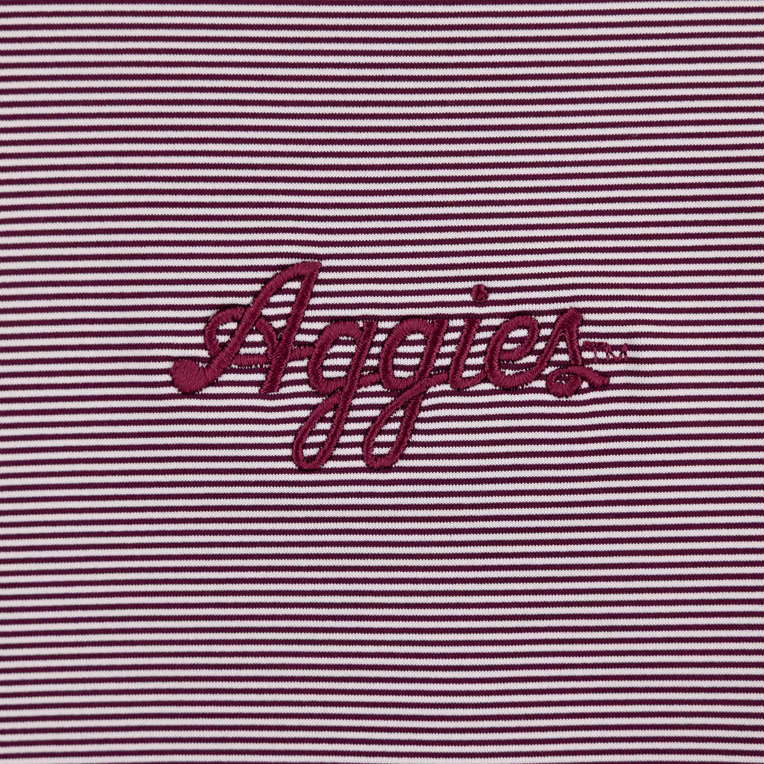 Close up of Maroon Script Aggies text on chest of maroon and white polo