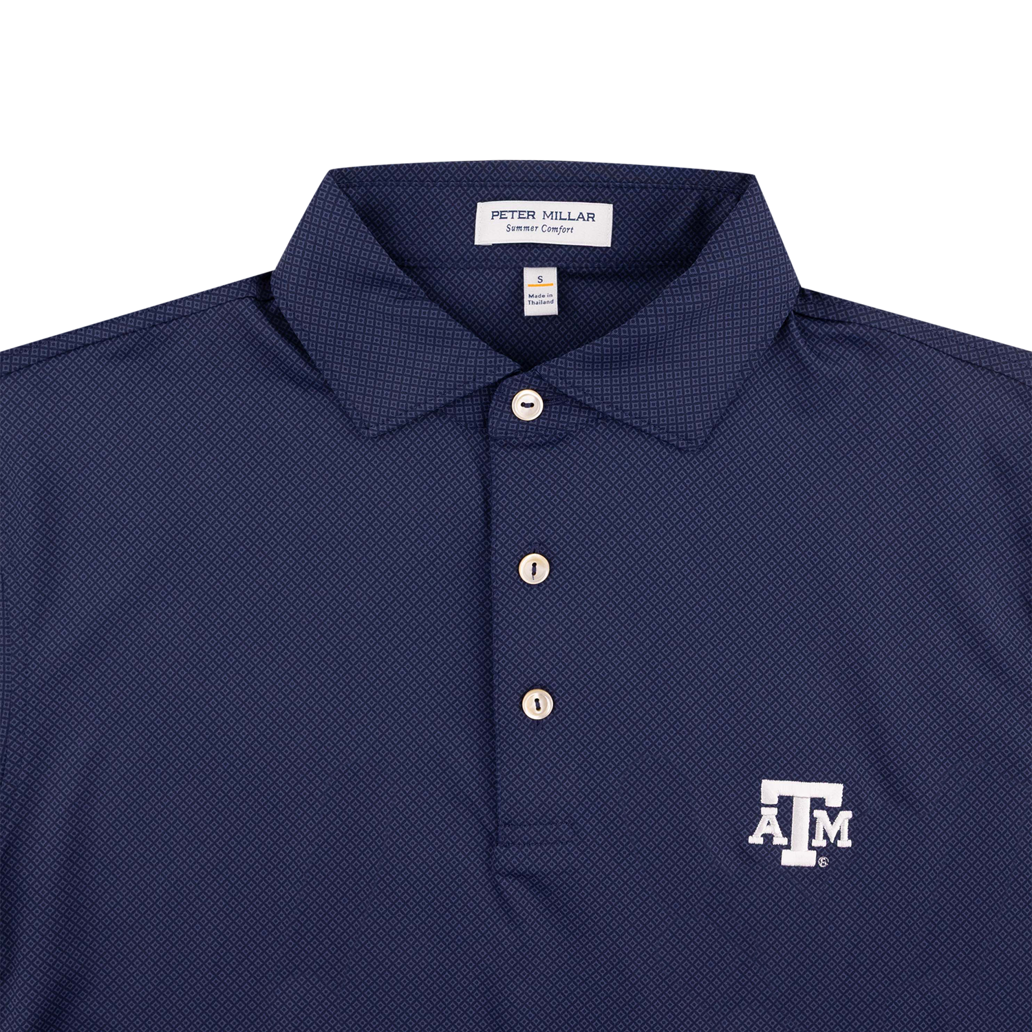 Close-up of a navy blue polo shirt with a white embroidered Texas A&M 'A&M' logo on the left chest, featuring a three-button placket and a Peter Millar label on the collar.