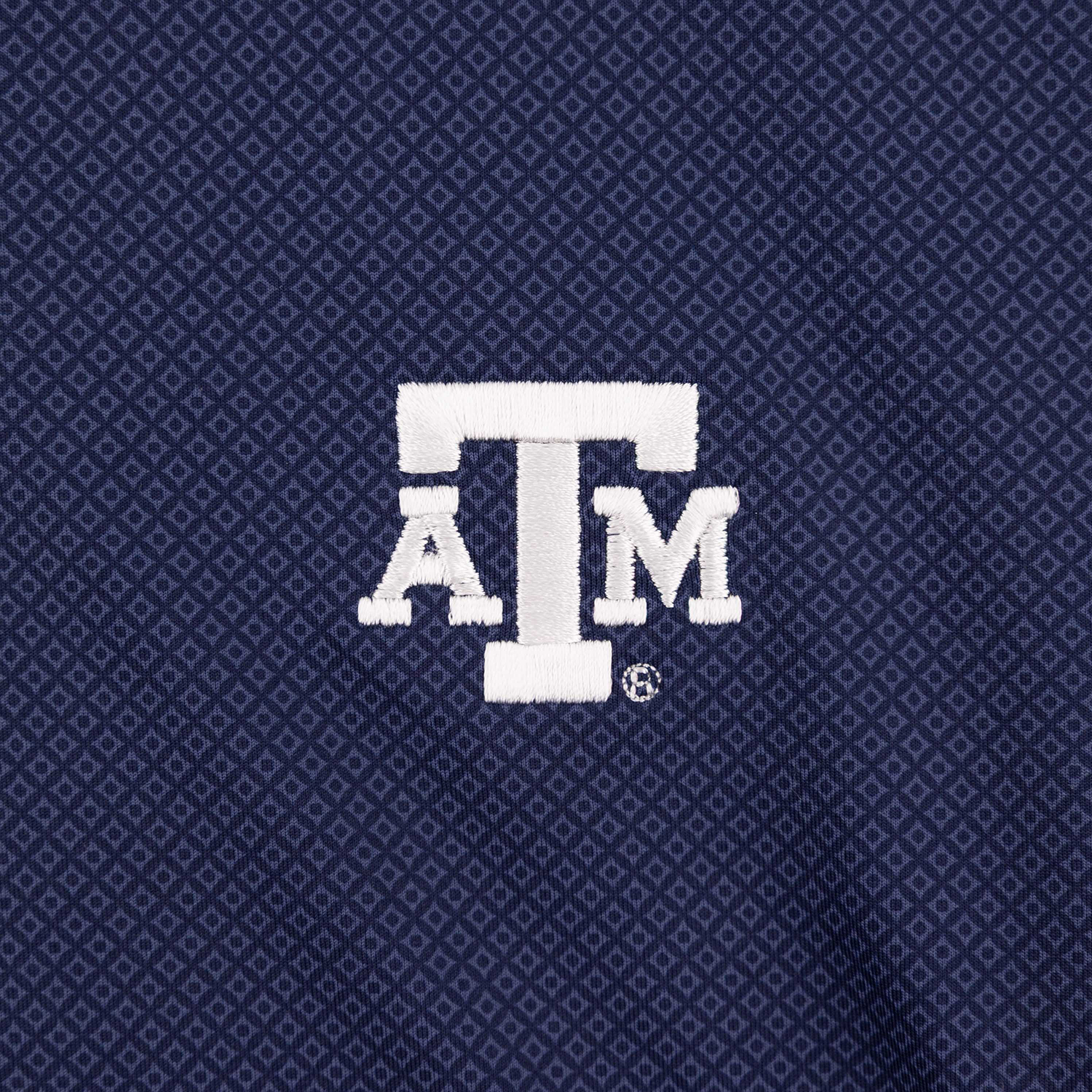 Close-up of a navy blue textured fabric with a repeating geometric pattern and a white embroidered 'ATM' logo in the center.