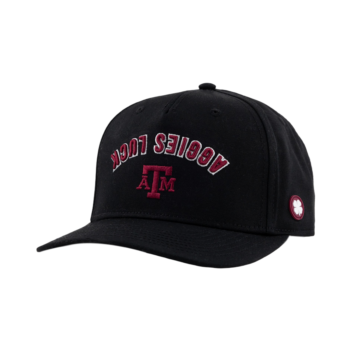 A black baseball cap featuring arched maroon and white text reading "AGGIES LUCK" above a maroon Texas A&M "ATM" logo, with a small white clover patch on the side panel.   