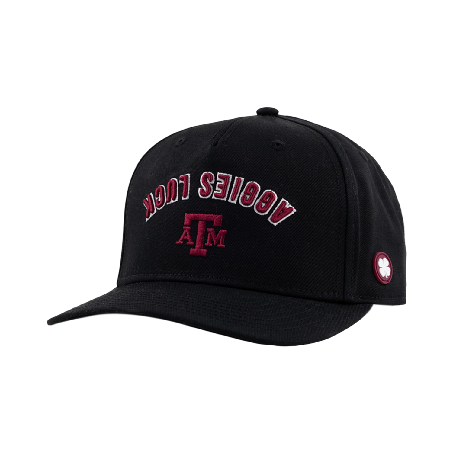 A black baseball cap featuring arched maroon and white text reading "AGGIES LUCK" above a maroon Texas A&M "ATM" logo, with a small white clover patch on the side panel.   