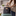 Person holding a black patterned tote bag with a visible brand logo in an indoor setting.