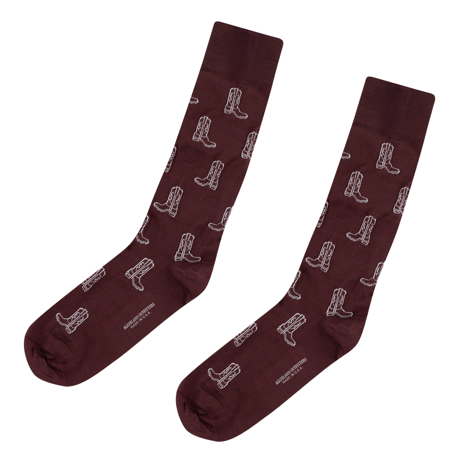 Pair of maroon crew socks with a repeating white cowboy boot pattern and "AGGIELAND OUTFITTERS MADE IN U.S.A." printed along the sole.   
