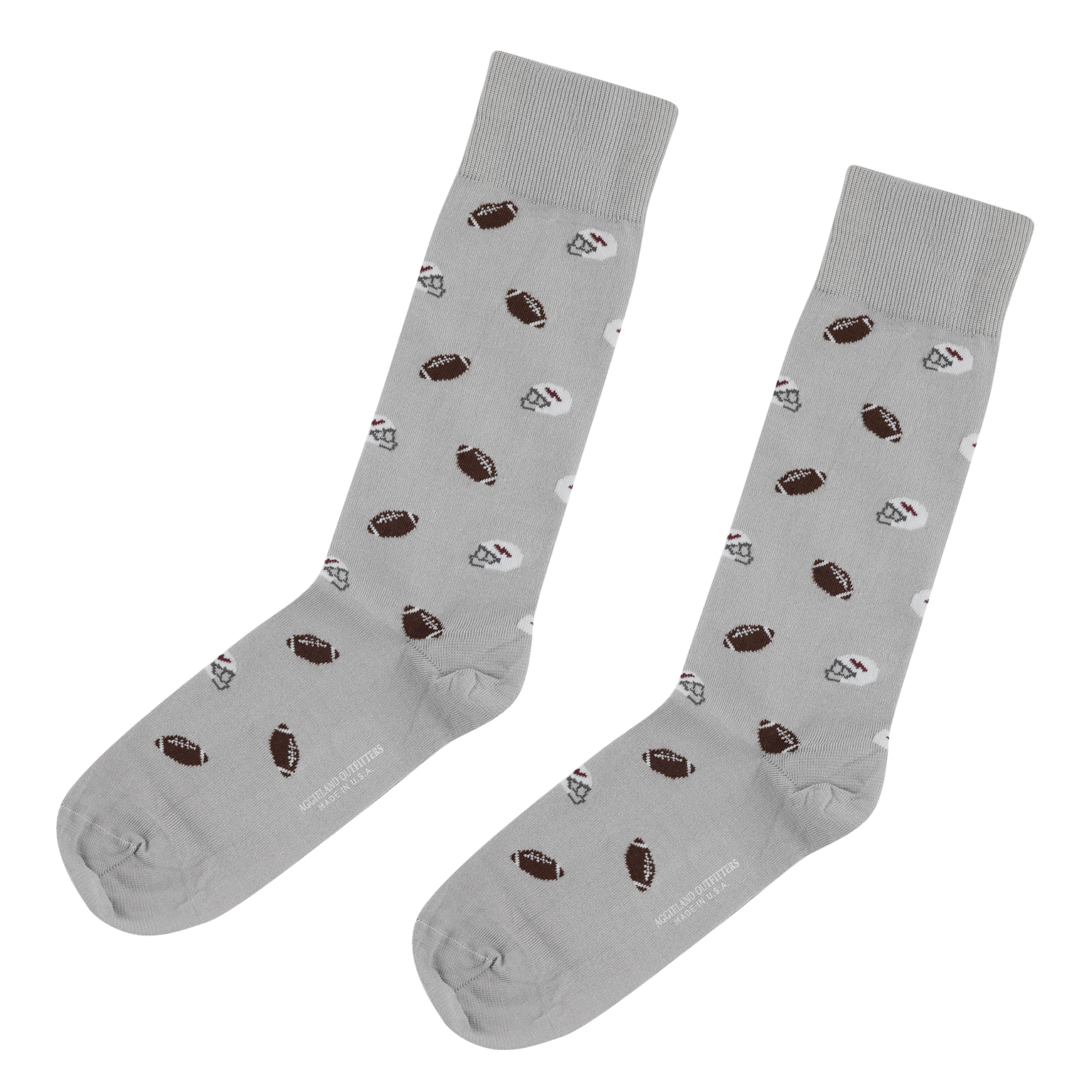 Pair of light gray crew socks with a repeating pattern of small footballs and white football helmets, featuring "AGGIELAND OUTFITTERS MADE IN U.S.A." printed along the sole.   