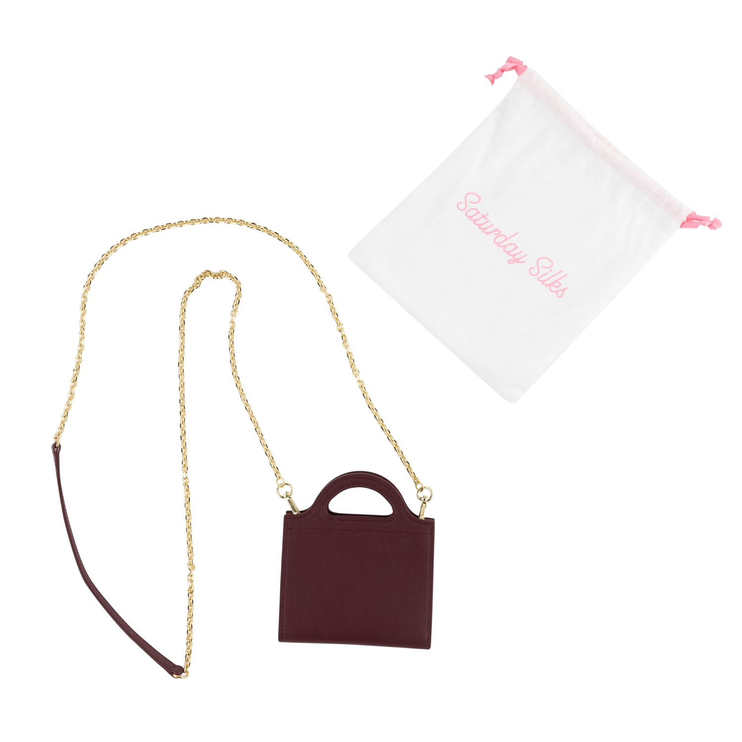 A miniature burgundy handbag with a gold chain strap, shown next to a white drawstring bag with pink branding that reads 'Saturday Silks'.