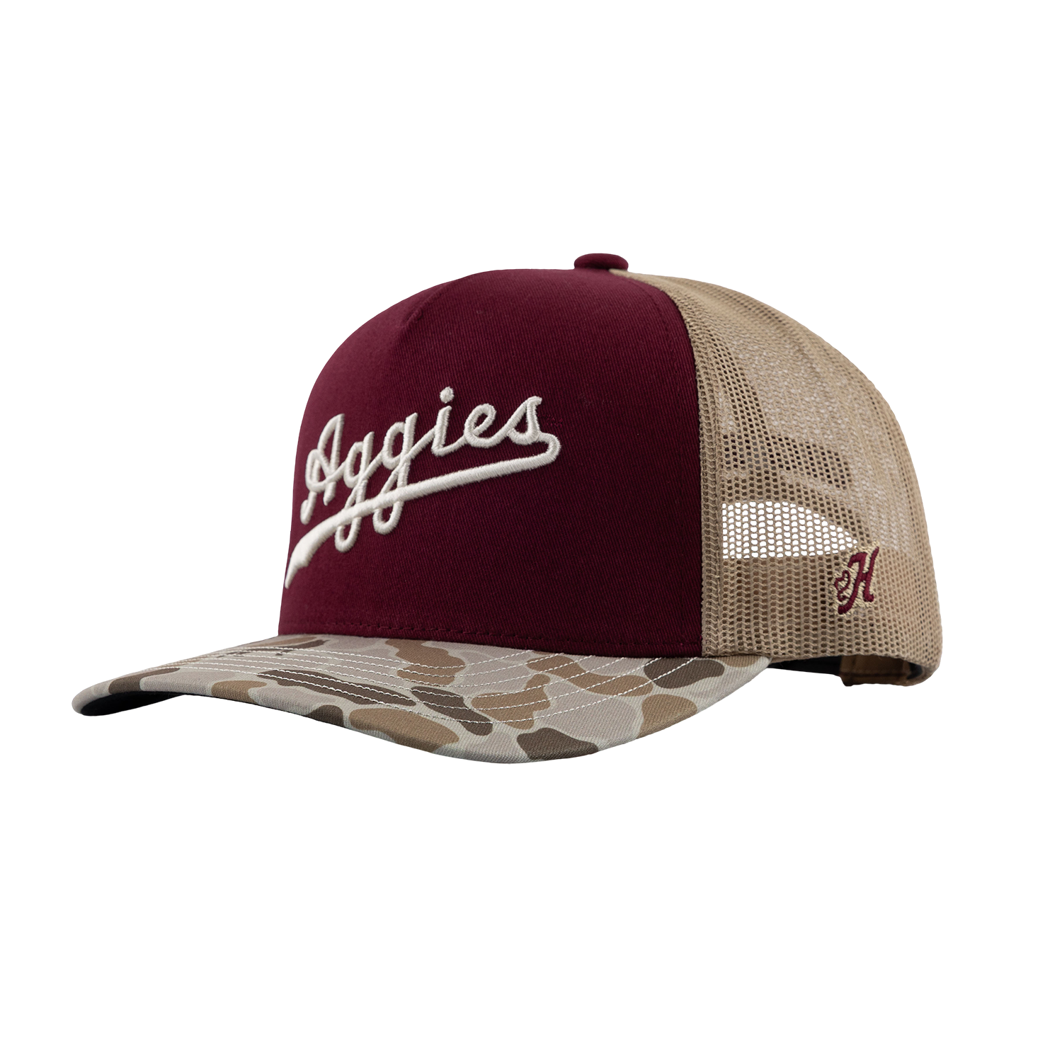 A trucker-style baseball cap with a maroon front panel, beige mesh back, and a camouflage-patterned brim. The front features white embroidered script reading 'Aggies', and the side displays a small maroon embroidered Hooey brand 'H'.