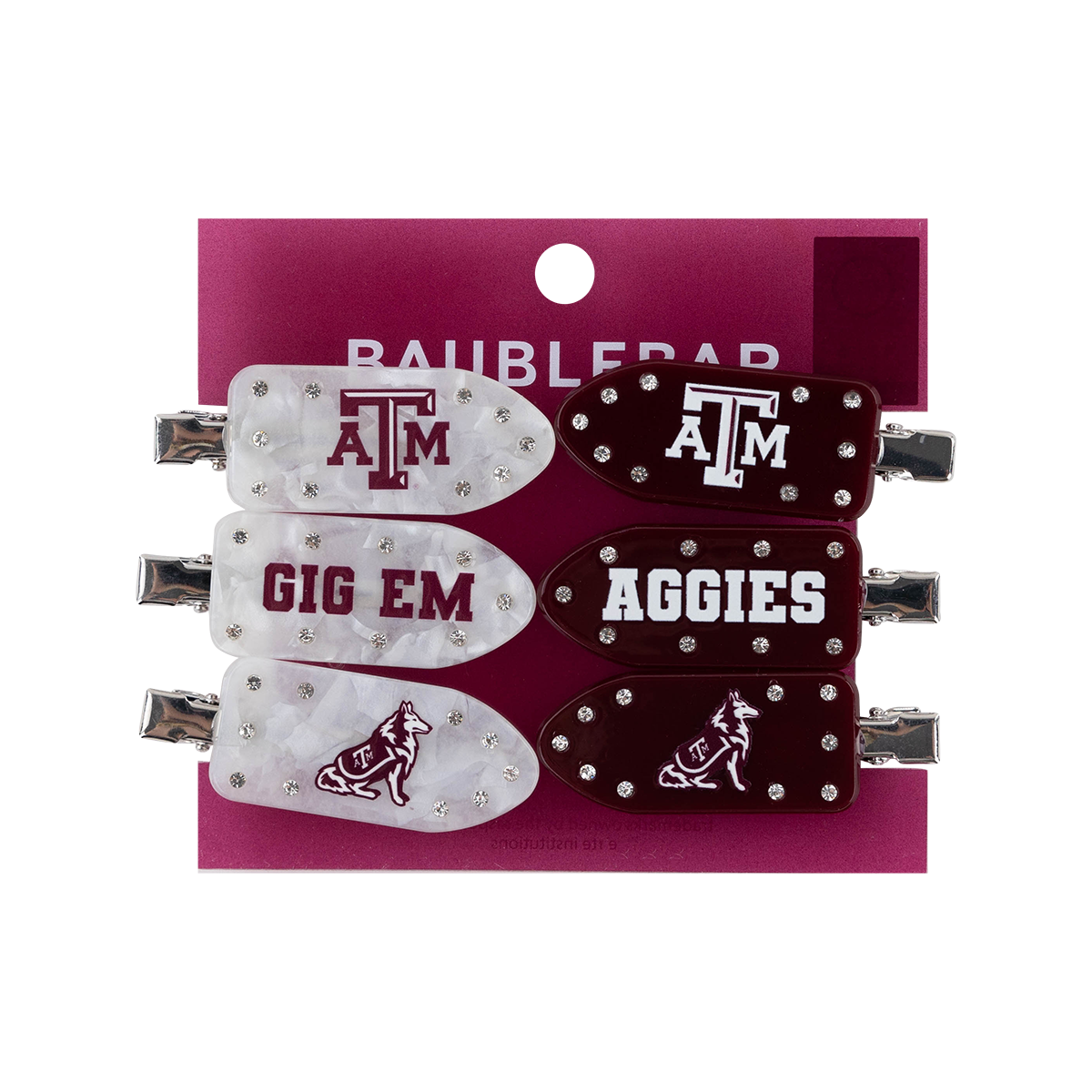 Four hair clips on a magenta backing card. The clips are white and maroon with silver rhinestone accents and feature Texas A&M University branding, including the 'ATM' logo and the word 'AGGIES'.
