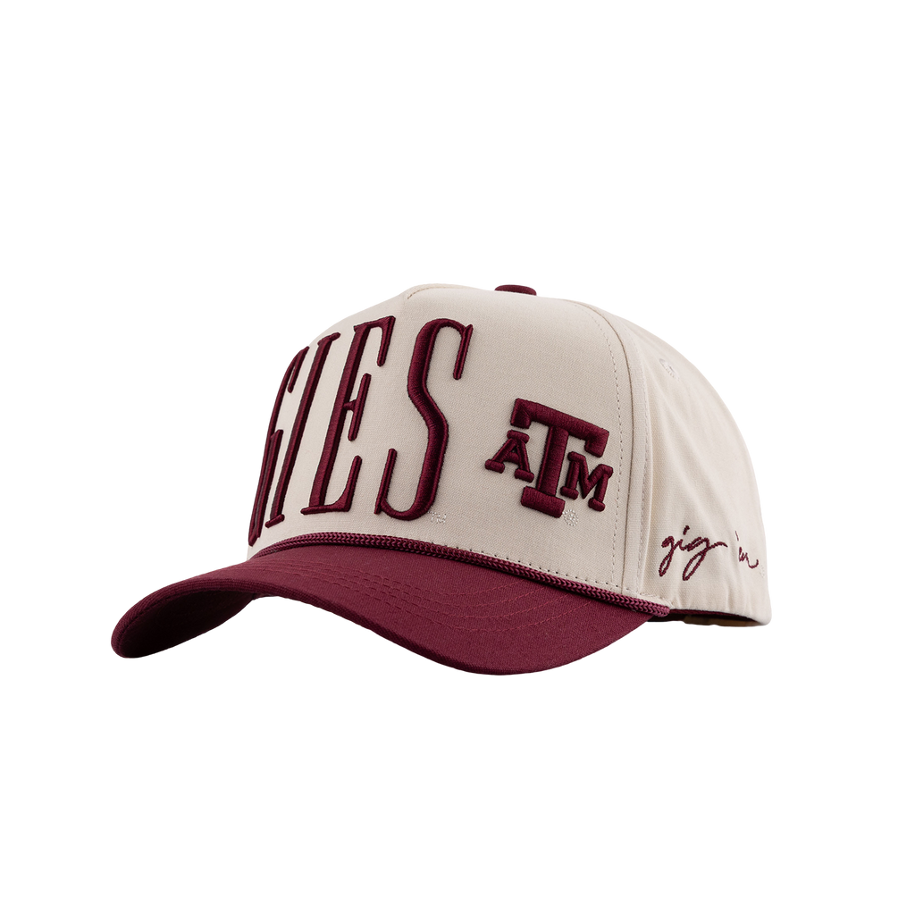 A baseball cap featuring a cream-colored crown with maroon embroidered lettering that reads 'AGGIES' and 'A&M', plus a small script logo on the side, set against a plain white background.