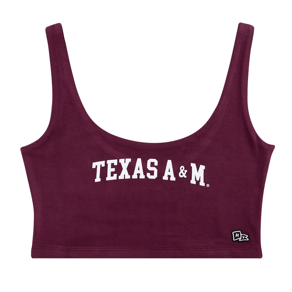 A maroon tank top crop top. There is white block lettering across the chest spelling "TEXAS A&M". In the bottom left corner there is a small black and white brand logo. It is a scoop neck line.